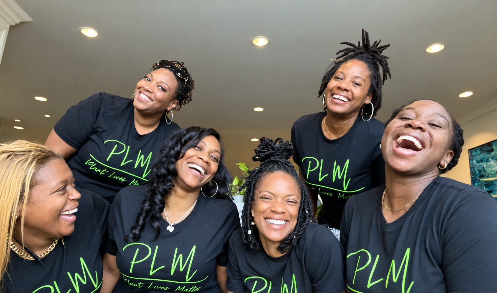 Five people smiling together in black Plant Lives Matter Script tees